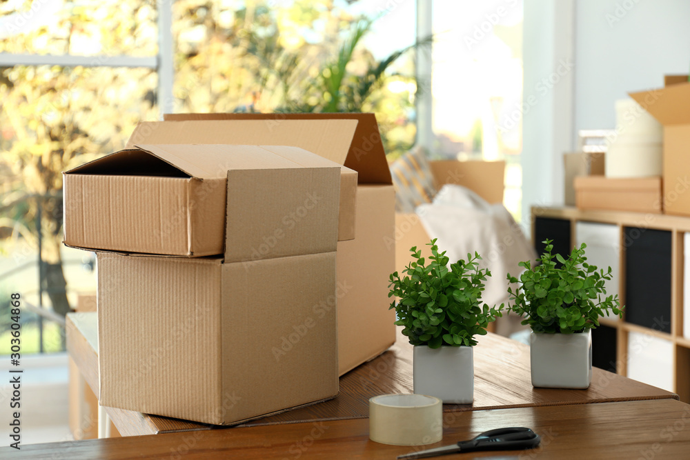 Cardboard boxes and potted plants on wooden table. Moving day Cardboard boxes and potted plants on wooden table. Moving day