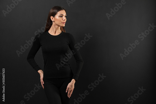 Woman wearing thermal underwear on black background. Space for text