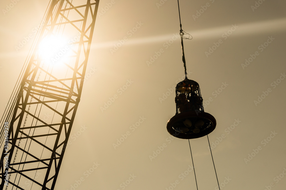 Φωτογραφία Silhouette of personal transfer basket being lifteed by a crane at oil field