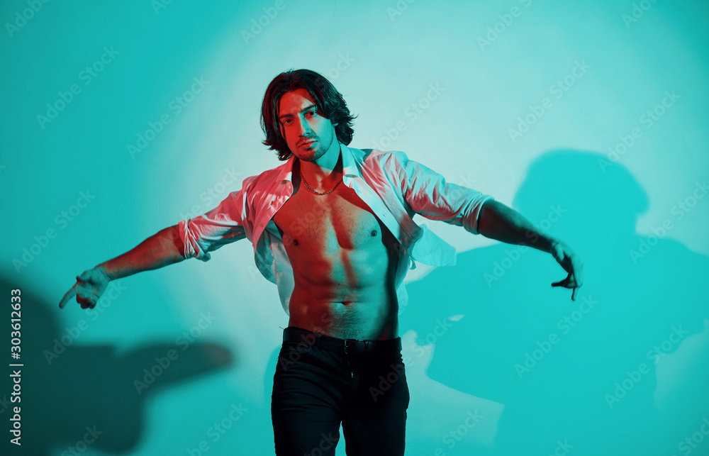 Portrait of young hot man that stands in neon lights in the studio Portrait of young hot man that stands in neon lights in the studio