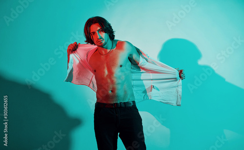 Portrait of young hot man that stands in neon lights in the studio