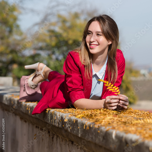 Woman in red suit resting in autumn park