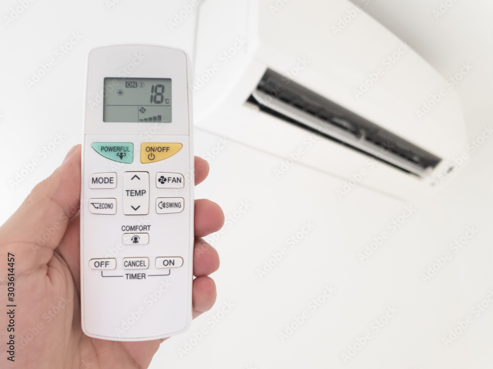 Modern airconditioner unit with a hand holding a remote. Modern airconditioner unit with a hand holding a remote.