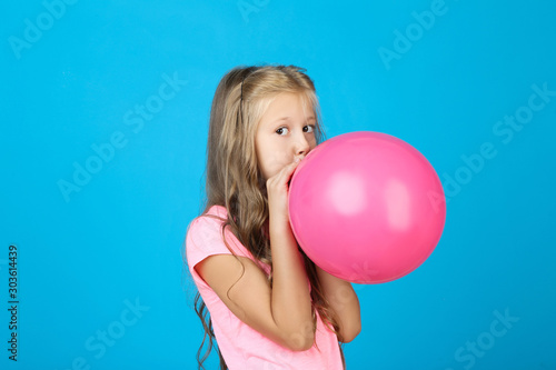 Pretty little girl blowing pink balloon on blue background © 5second