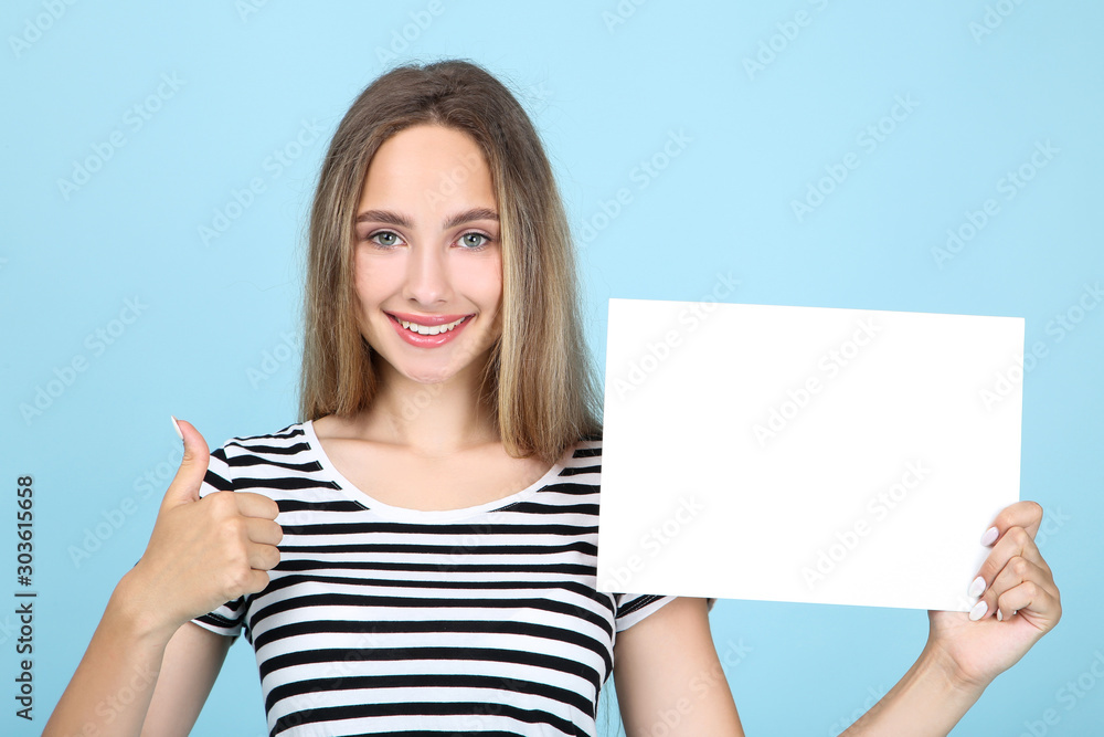 Beautiful young woman holding white blank board and showing thumb up on blue background Beautiful young woman holding white blank board and showing thumb up on blue background
