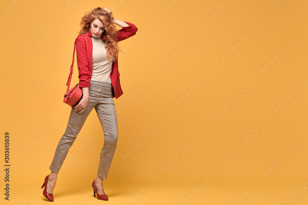 Fashion. Beautiful woman in red jacket, trendy curly hair, make up. Adorable well dressed redhead girl on orange. Gorgeous fashionable lady in red heels, hairstyle, makeup. Creative beauty shot Fashion. Beautiful woman in red jacket, trendy curly hair, make up. Adorable well dressed redhead girl on orange. Gorgeous fashionable lady in red heels, hairstyle, makeup. Creative beauty shot