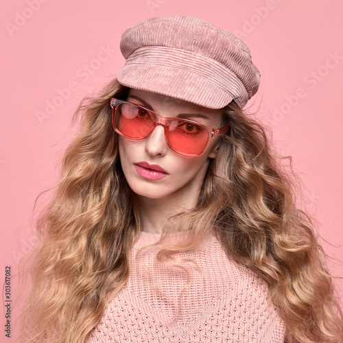 Fashionable lovable woman in Trendy pink outfit, stylish hairstyle, makeup smiling. Young blonde in jumper. Sensual beautiful model girl in stylish sunglasses, pastel fashion beauty concept on pink © evgenij918