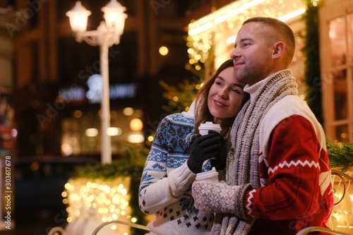 Charming couple feels happy while enjoying Christmas Eve on decorated street.
