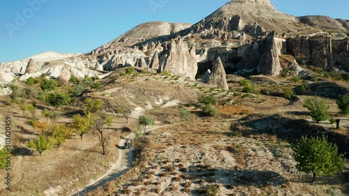 A young woman rides a quad bike through the landscapes of Cappadocia, Turkey. Aerial follow shot from a drone photo