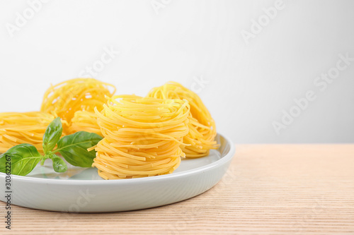 Uncooked tagliatelle pasta on wooden table against grey background