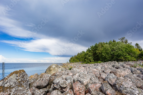 Boulders, forest, shore, evening light, sunset, clouds, blue sky and rainbow on the Baltic Sea. Mohni, small island in Estonia, Europe. photo