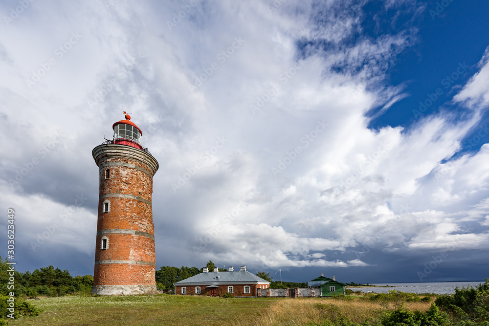 Lighthouse and house in the Baltic Sea. Shore, evening light, sunset, clouds and architecture concept. Mohni, small island in Estonia, Europe.