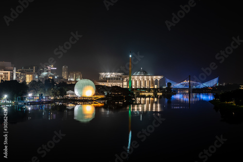 Night scene with colorful mosque, hot air balloon and bridge with reflections on river in Putrajaya, Malaysia.