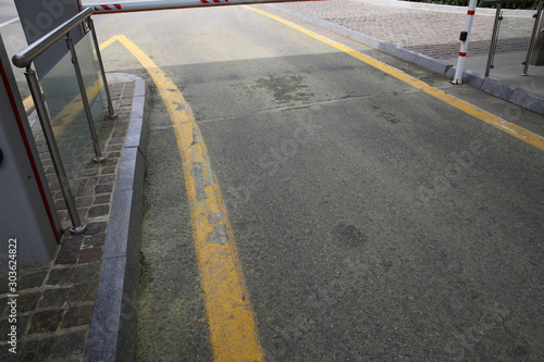 the road under the barrier. The road is covered with yellow . Barrier on the car parking .