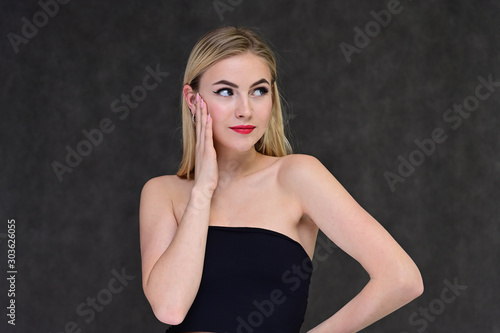 The concept of fashionable glamor, cosmetics and beauty with a pretty girl. Portrait of a fashionable beautiful blonde model with long hair, great makeup, on a gray background. © Вячеслав Чичаев