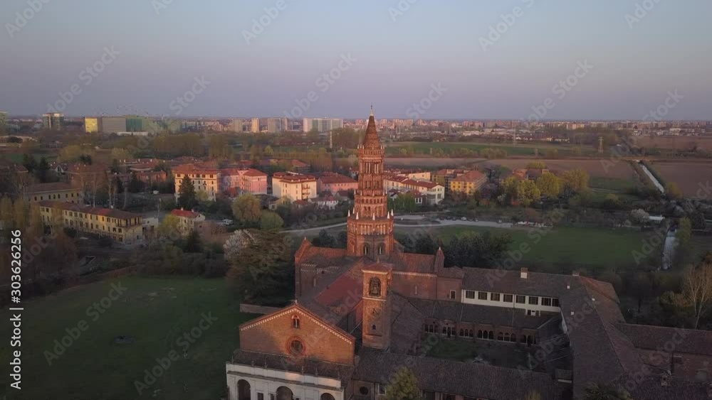 4k aerial drone forward footage at sunset time of Chiaravalle abbey, the ancien and prestigious italian monument located in the south of Milan city.