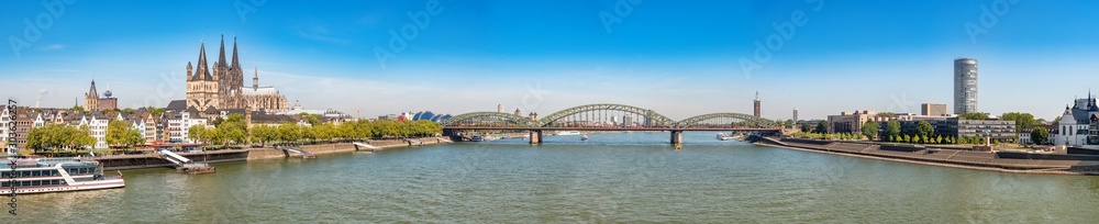 Panorama of the Hohenzollern bridge over Rhine river on a sunny day. Beautiful cityscape of Cologne, Germany  with cathedral and Great St. Martin Church in the background