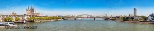 Panorama of the Hohenzollern bridge over Rhine river on a sunny day. Beautiful cityscape of Cologne  Germany  with cathedral and Great St. Martin Church in the background