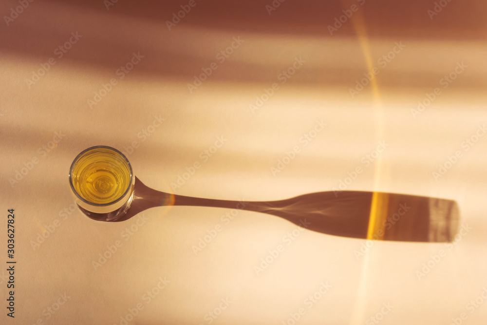 Glass of champagne on a light background. An impressive long shadow falls from the glass. The original concept of the holiday, alcoholic drinks. Minimalism, top view.