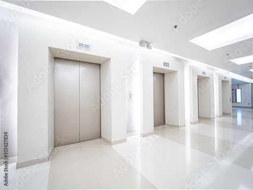 Modern steel elevator cabins in a business lobby or Hotel  Store  interior  office perspective wide angle. Three elevators in hotel lobby.