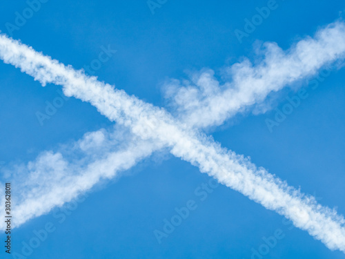 Traces of planes intersect in the blue sky