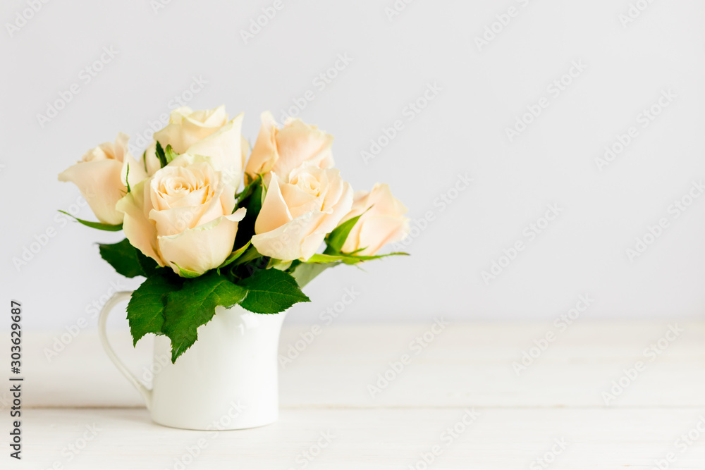 Obraz premium Romantic bouquet of pastel cream roses in a jar on a white background.