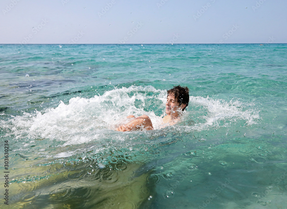 boy dives backwards into the clear waters of the sea