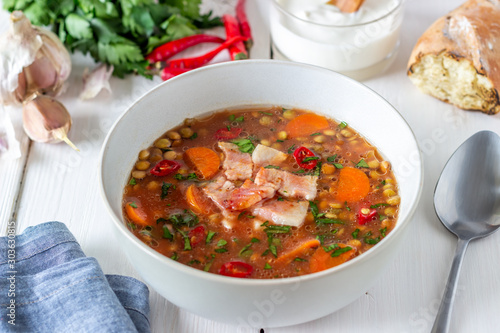 Lentil soup with carrots and fried bacon. Recipes. German cuisine. Wooden background.