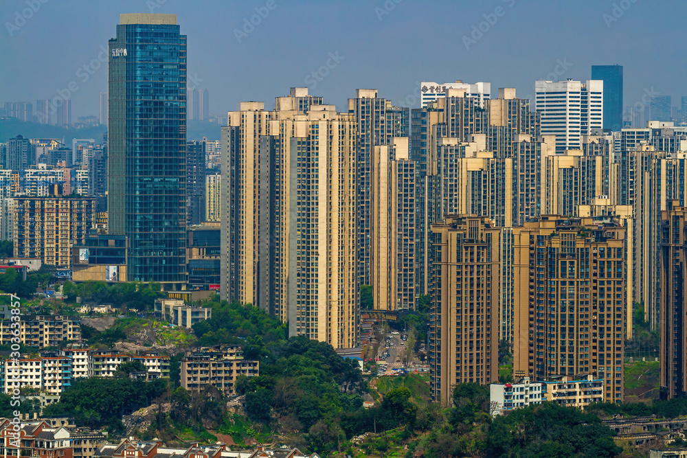 Fototapeta premium Chongqing, China - March 20, 2018: City blocks on the hills. Top view of the Chinese city of Chongqing. Sunny day in metropolis.