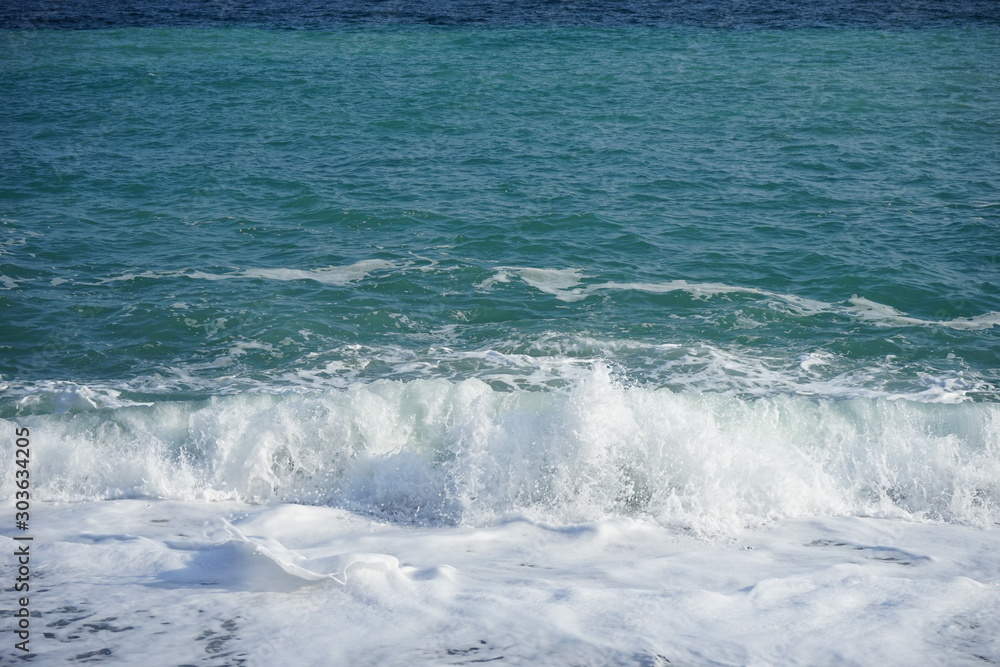 Splashing waves in a storm at sea with blue sky