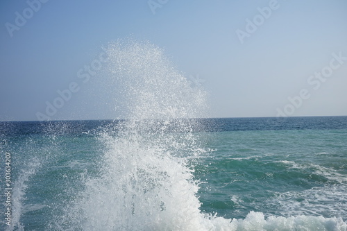Splashing waves in a storm at sea with blue sky
