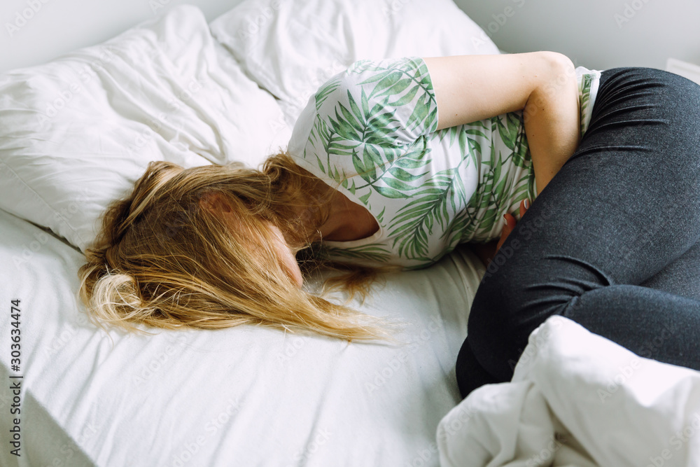 Woman lying on the bed and having stomach ache Woman lying on the bed and having stomach ache
