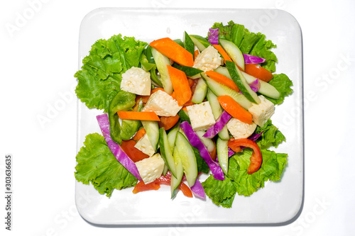 Fresh green vegetable salad in a plate. Healthy capsicume, carrot, cheese, tomato and lettuce meal on white background