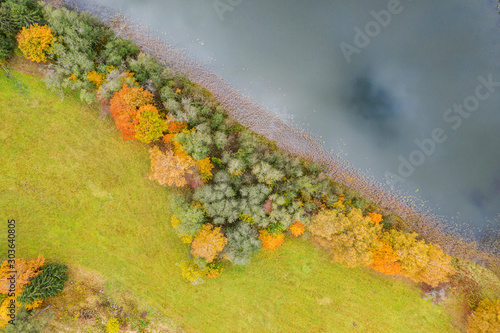 Forest in autumn colors. Colored trees and a meandering blue river. Red, yellow, orange, green deciduous trees in fall. Veclaicene, Latvia, Europe photo