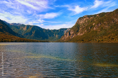 Wide angle landscape view of the Bohinj Lake (Bohinjsko jezero) and scenic mountain gorge in the background. Concept of landscape and nature, sunny day. Triglav National Park, Slovenia