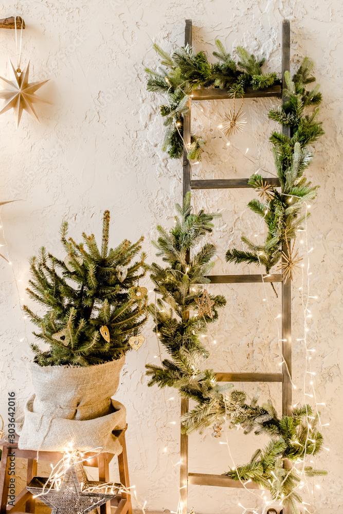 Christmas, New Year decor with a Christmas tree in a pot, fir branches and burning garlands. Traditional winter holidays Christmas / New Year. 