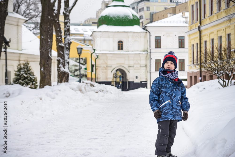 Little boy walking in the park. Child going for a walk after school with a school bag in winter. Children activity outdoors in fresh air. Healthy way of life concept
