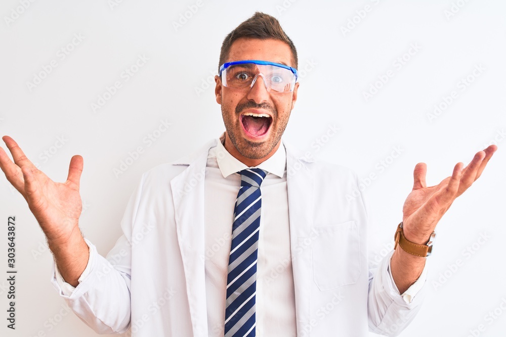 Young handsome scientist man wearing safety glasses over isolated background celebrating crazy and amazed for success with arms raised and open eyes screaming excited. Winner concept Young handsome scientist man wearing safety glasses over isolated background celebrating crazy and amazed for success with arms raised and open eyes screaming excited. Winner concept