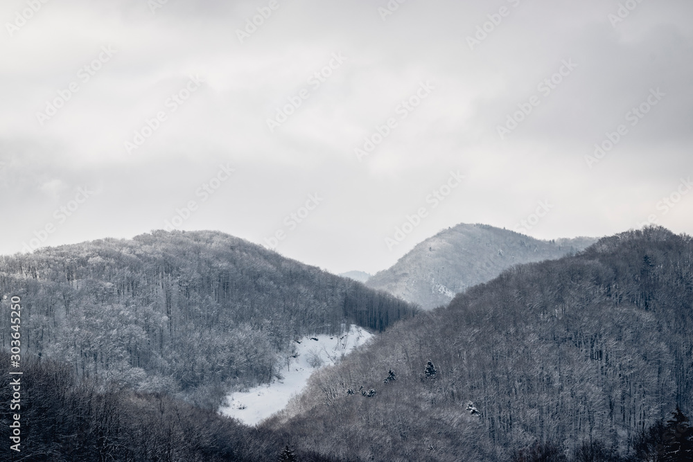 Hills covered in fresh snow under a cloudy sky