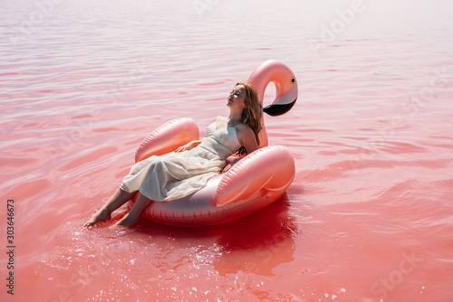 Beautiful woman lying on inflatable float mattress on pink sea photo