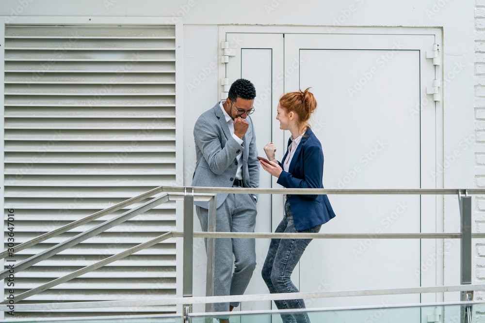 Happy couple using smart phone while standing near door Happy couple using smart phone while standing near door