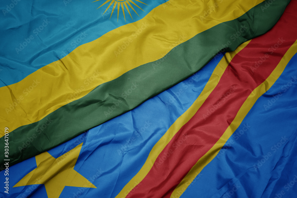 waving colorful flag of democratic republic of the congo and national flag of rwanda.