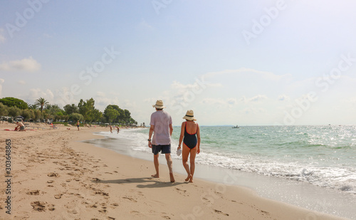 An older couple walking along the nice and sandy beach near a campsite in northern spain, at the costa brava