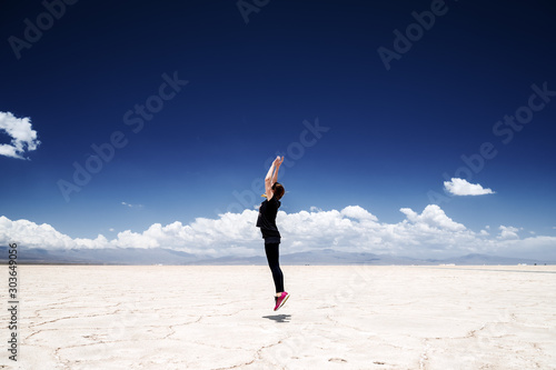 Young woman jumps straight in the Salinas Grandes salt flats in Jujuy, Argentina photo