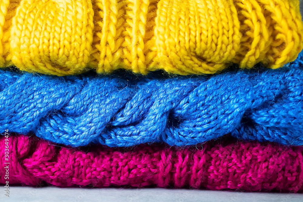 Knitted bright multi-colored things on a gray background. DIY things concept. Knitted bright multi-colored things on a gray background. DIY things concept.