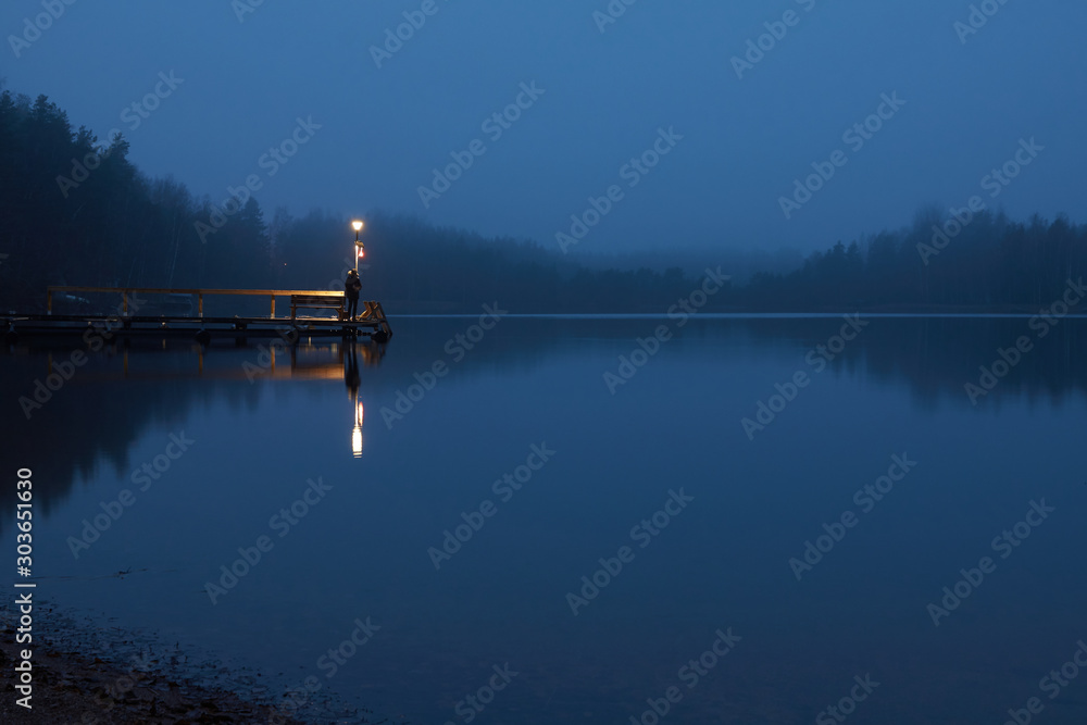 Dawn on the lake in the fog. Lantern on the dock.