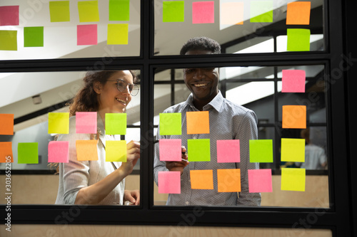 Happy mixed race colleagues standing near window glass board. photo