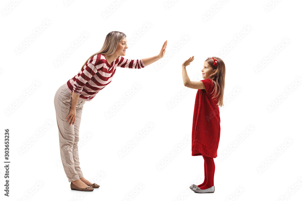 Young woman making a high-five gesture with a girl in a red dress Young woman making a high-five gesture with a girl in a red dress
