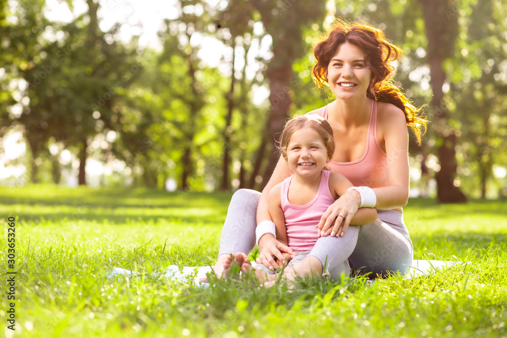 mother and daughter sitting in the park together and smiling at the camera