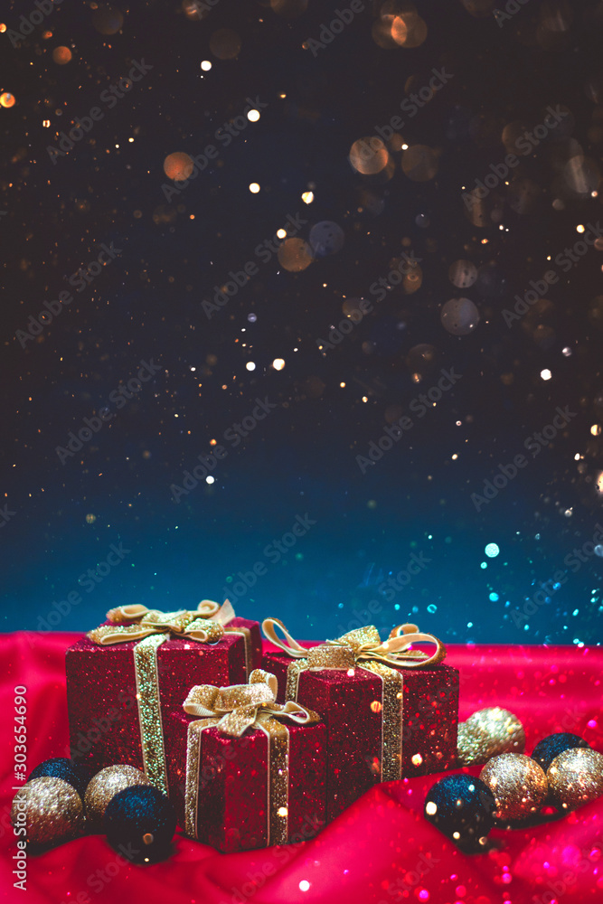 Three red present boxes with Christmas lights and decorations on a red and blue background with bokeh Three red present boxes with Christmas lights and decorations on a red and blue background with bokeh